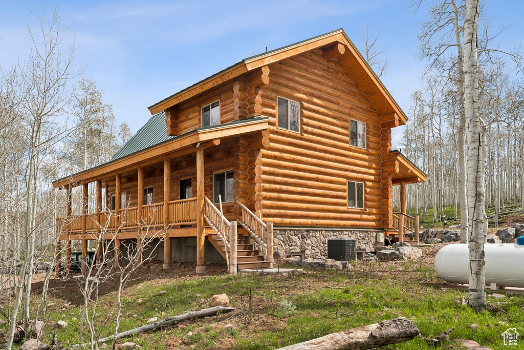 Rear view of property with log siding, stairs, covered porch, and metal roof