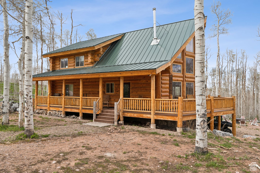 Log-style house featuring a porch and metal roof