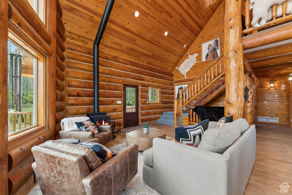 Living area with a wood stove, high vaulted ceiling, stairs, wood ceiling, and wood finished floors