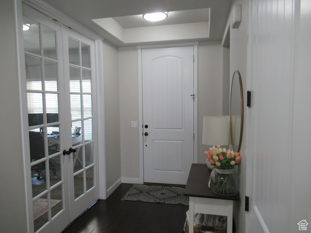 Doorway to outside with baseboards, french doors, dark wood-type flooring, and a tray ceiling