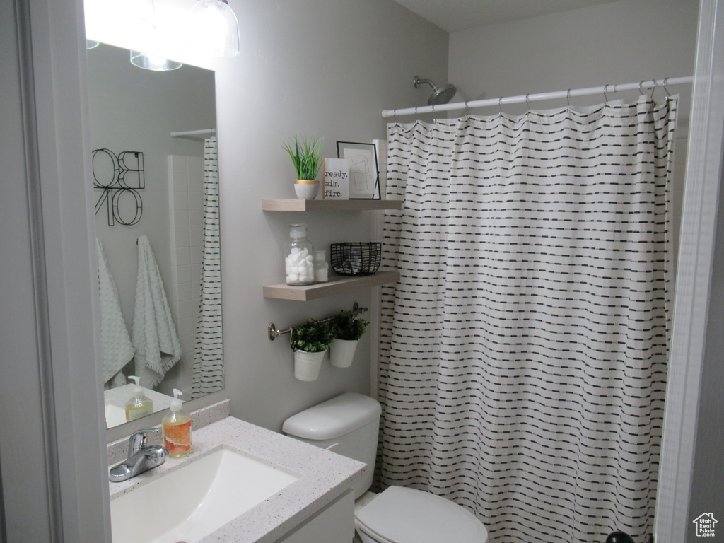 Bathroom with toilet, vanity, and a shower with curtain