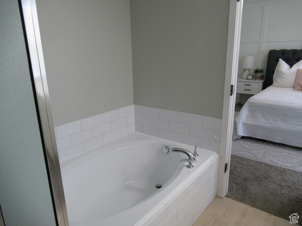 Ensuite bathroom featuring a bath and wood finished floors