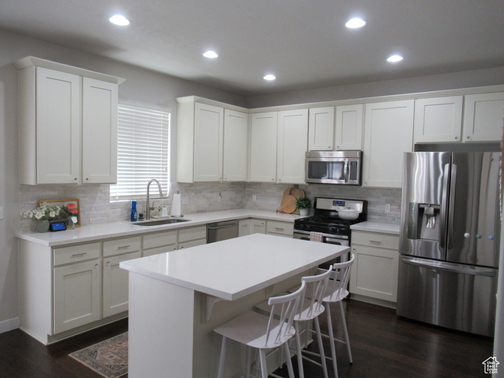 Kitchen with appliances with stainless steel finishes, a sink, dark wood finished floors, recessed lighting, and backsplash