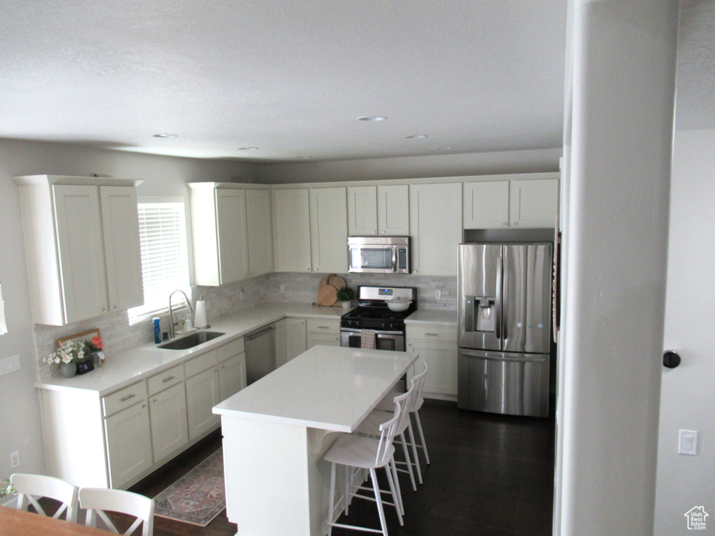 Kitchen with stainless steel appliances, a sink, tasteful backsplash, a center island, and a kitchen bar
