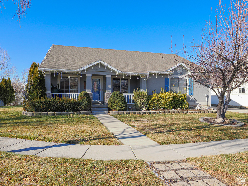 View of front of home featuring covered porch, a front yard, and stucco siding