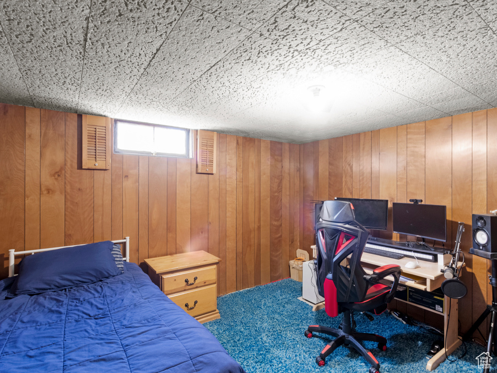 Bedroom with wood walls, a desk, and carpet floors