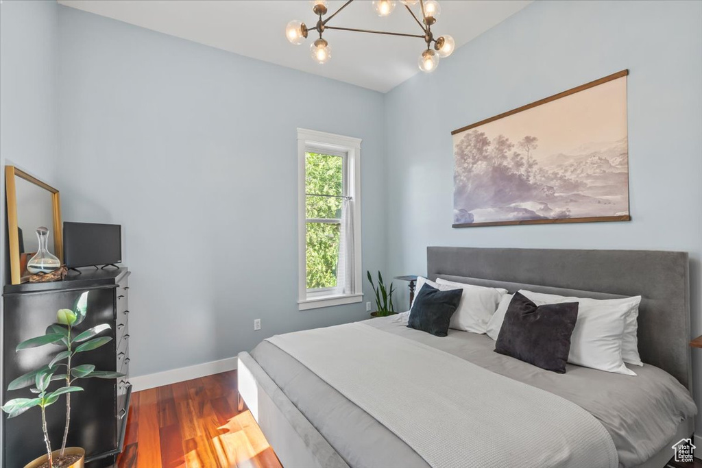 Bedroom featuring a chandelier, wood finished floors, and baseboards