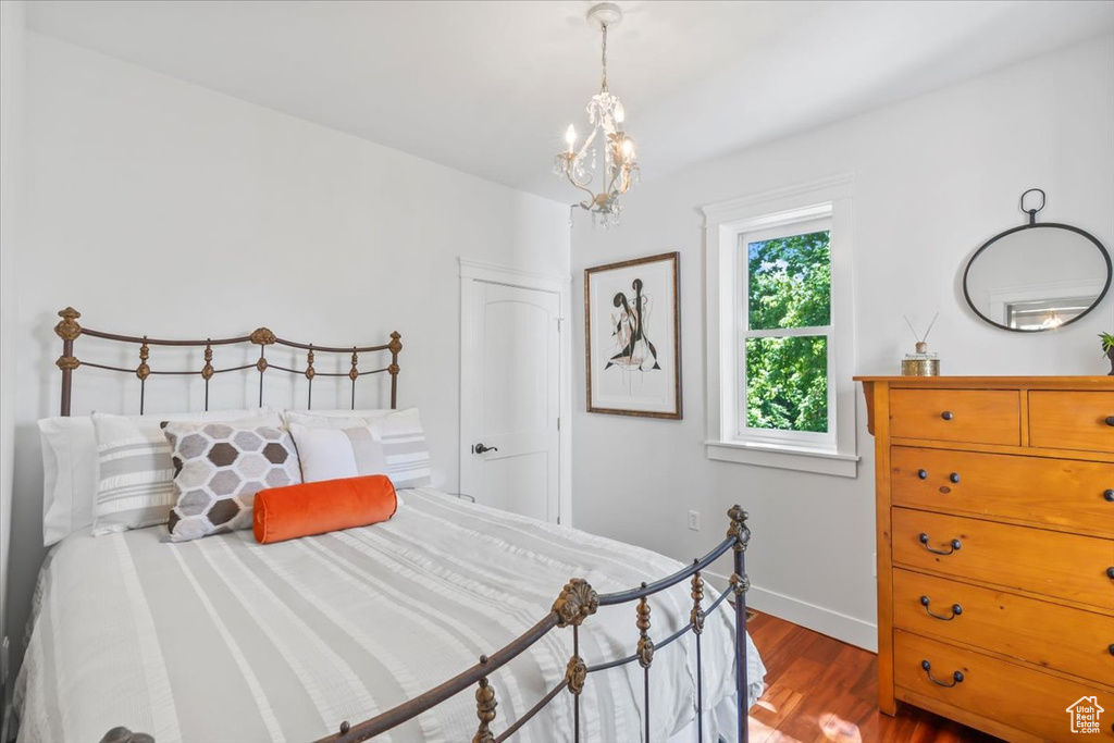 Bedroom with wood finished floors, a chandelier, and baseboards