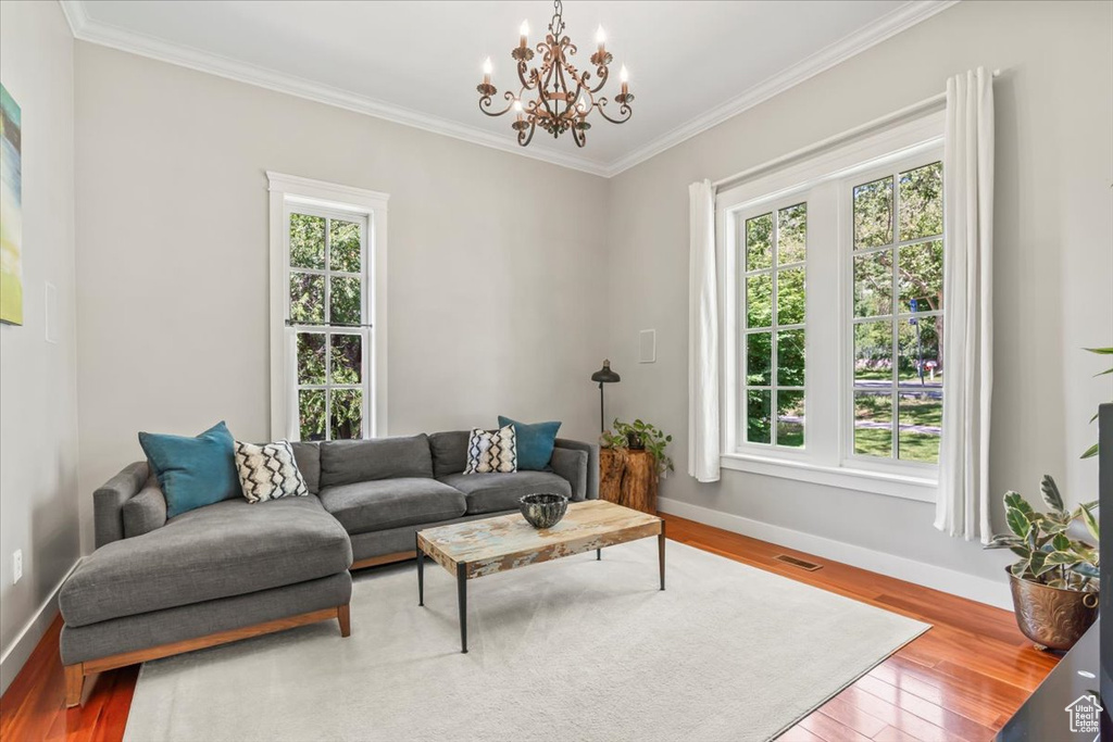Living area featuring plenty of natural light, baseboards, ornamental molding, and a chandelier