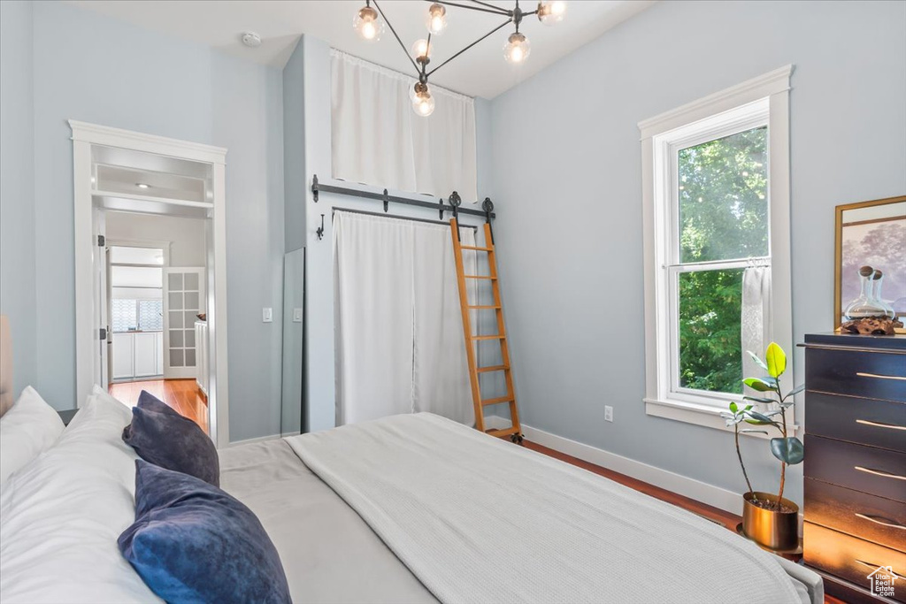 Bedroom with multiple windows, baseboards, a barn door, and wood finished floors