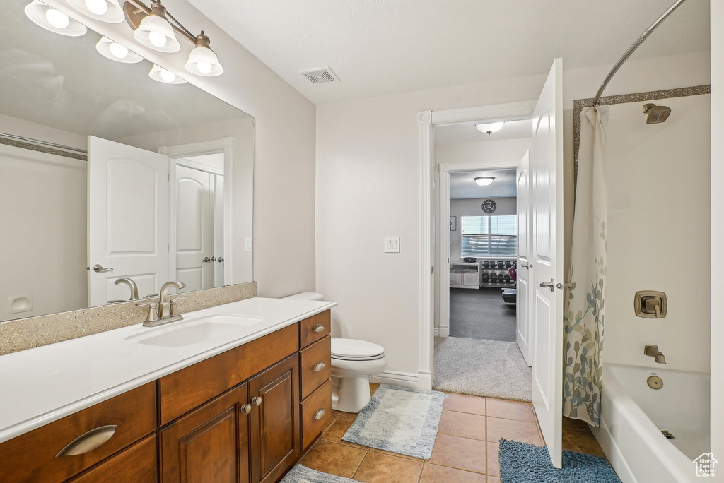 Bathroom featuring vanity, toilet, shower / tub combo with curtain, tile patterned flooring, and baseboards