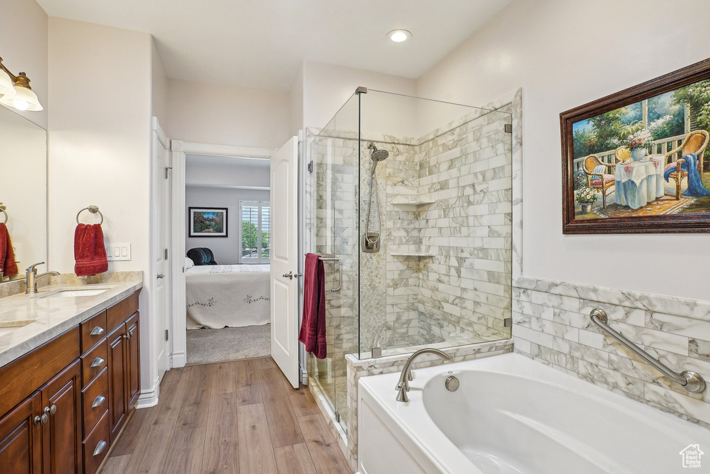 Ensuite bathroom with a garden tub, double vanity, a stall shower, wood finished floors, and recessed lighting