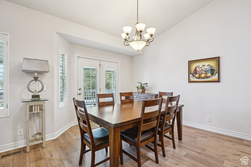 Dining area featuring a chandelier, light wood-style floors, baseboards, and lofted ceiling