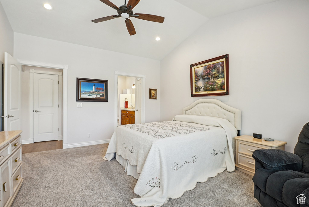 Bedroom featuring vaulted ceiling, recessed lighting, light carpet, baseboards, and ensuite bath