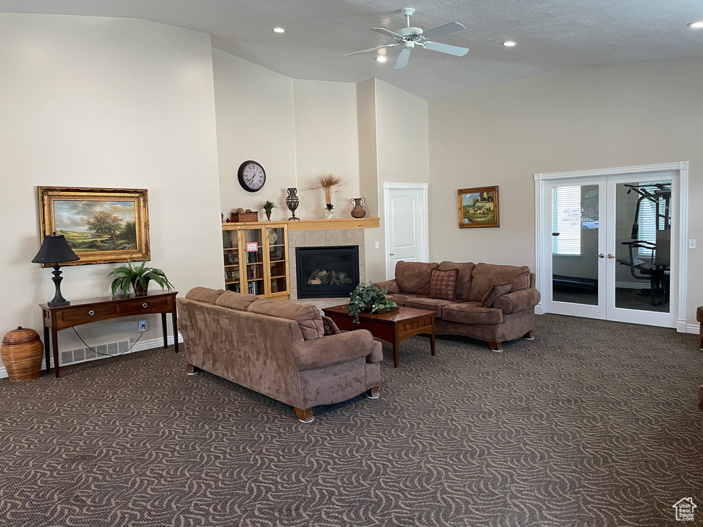 Living room featuring dark colored carpet, high vaulted ceiling, a ceiling fan, french doors, and a tile fireplace