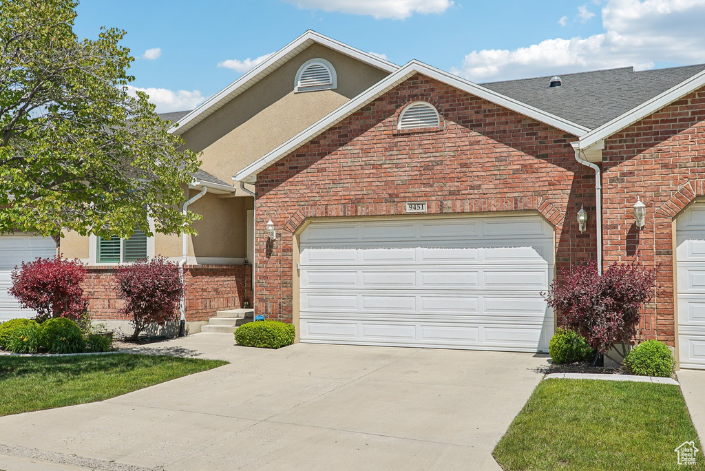 Traditional-style house with concrete driveway, an attached garage, stucco siding, and brick siding