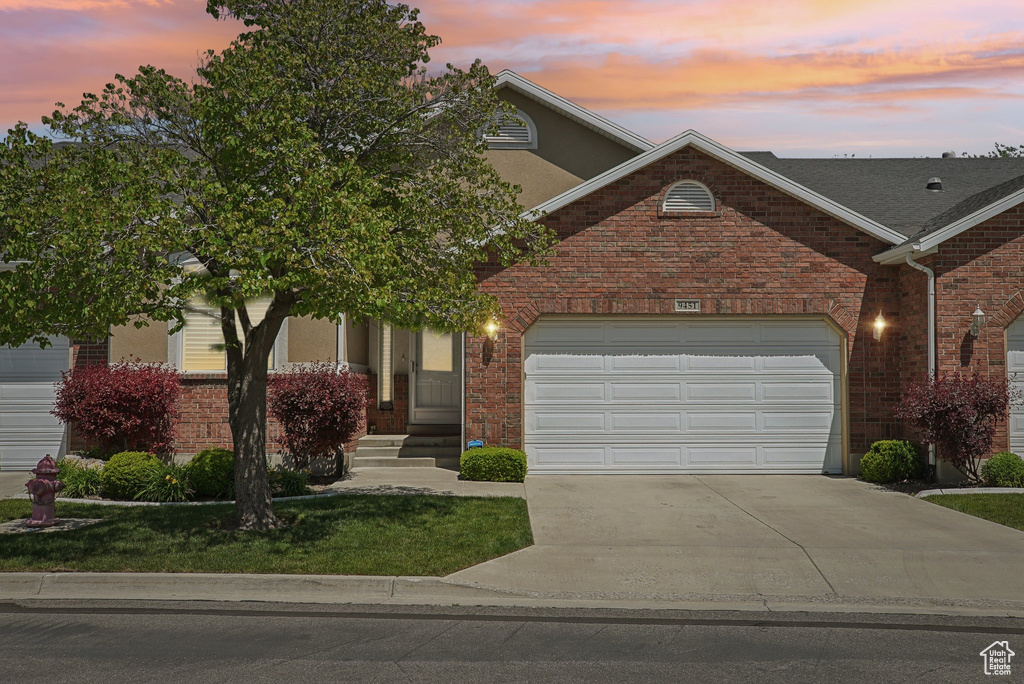 View of front of property with driveway, brick siding, a garage, and a front lawn