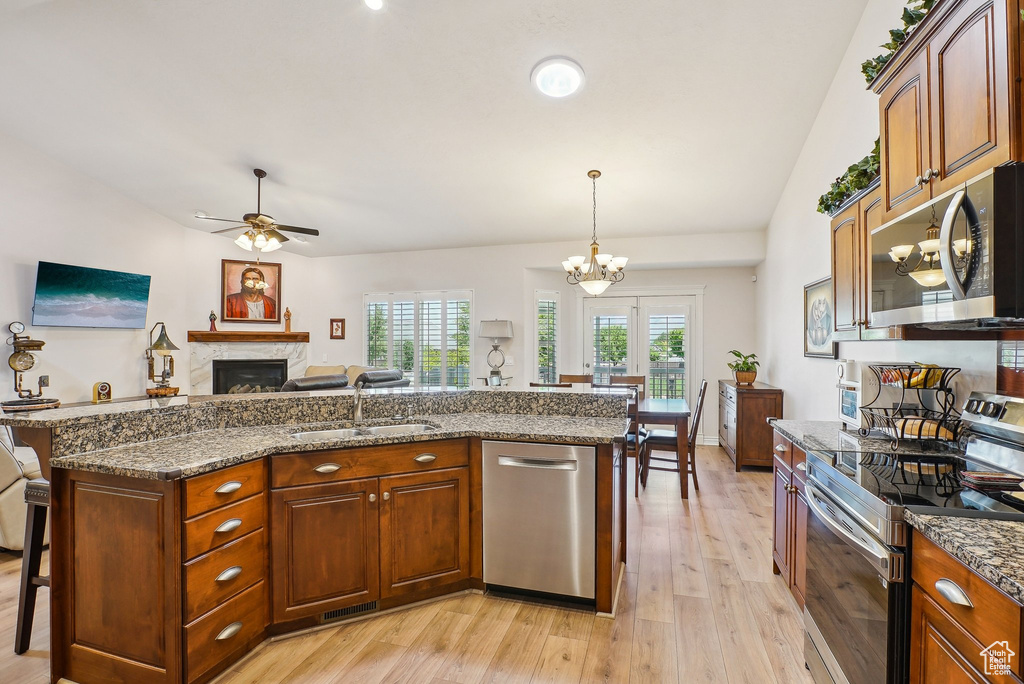 Kitchen with stainless steel appliances, a sink, a fireplace, light wood-style floors, and a breakfast bar