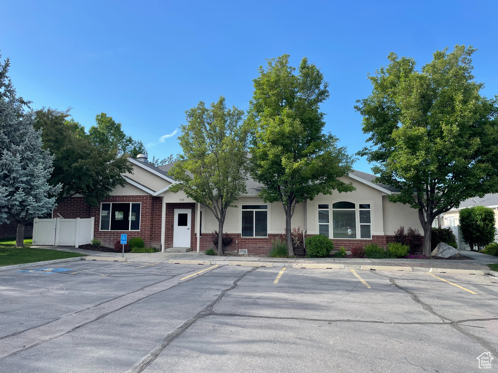 View of front of home with brick siding, uncovered parking, and stucco siding