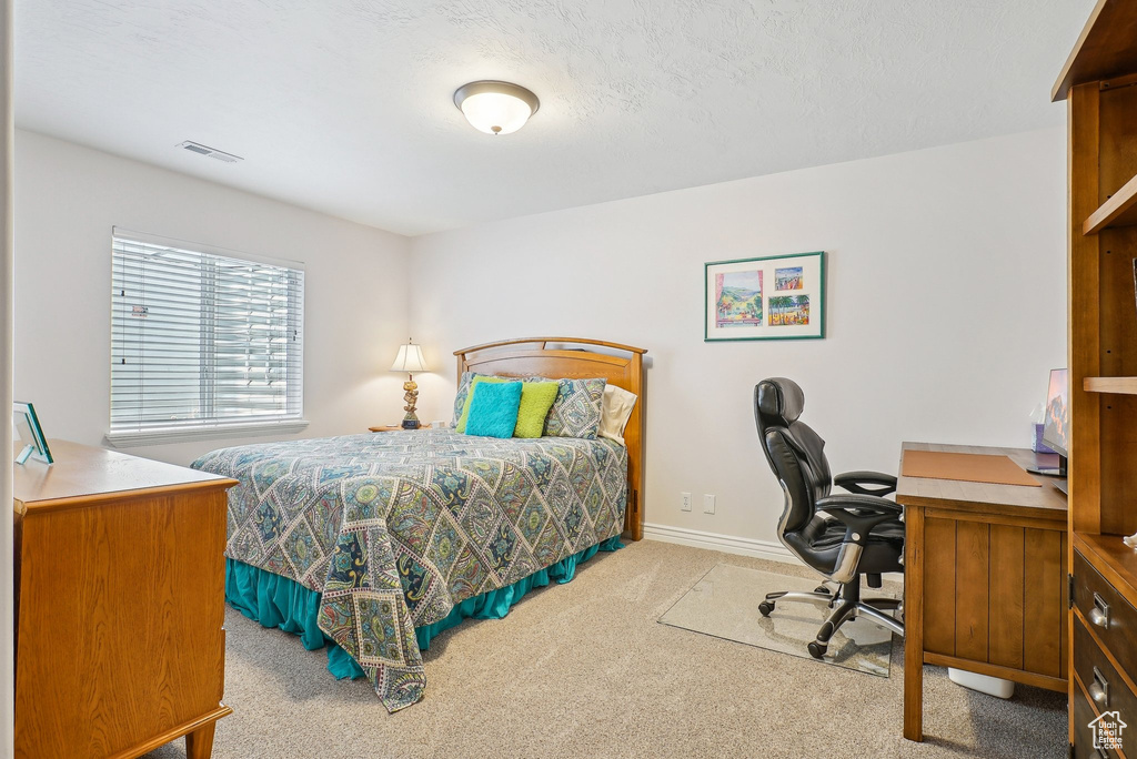 Carpeted bedroom with an office area and baseboards
