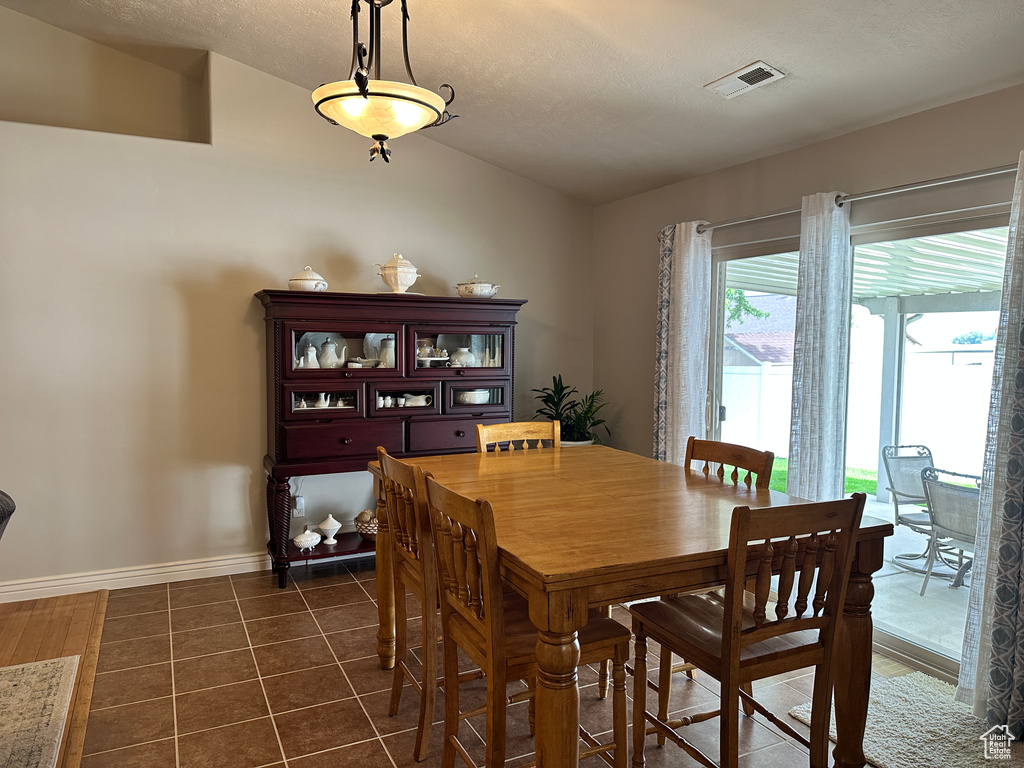 Dining area featuring lofted ceiling, baseboards, and dark tile patterned flooring