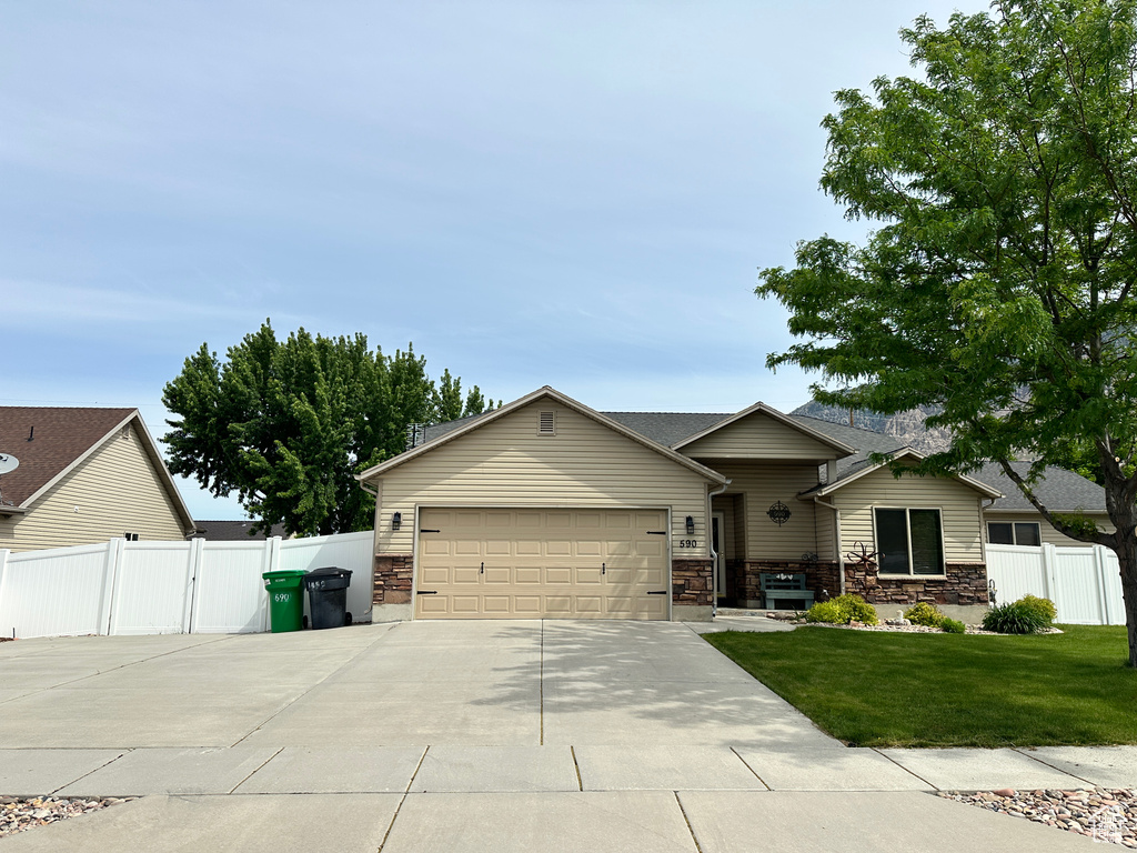 View of front of property with a garage, driveway, stone siding, and a gate