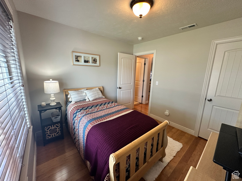 Bedroom featuring wood finished floors, baseboards, and a textured ceiling