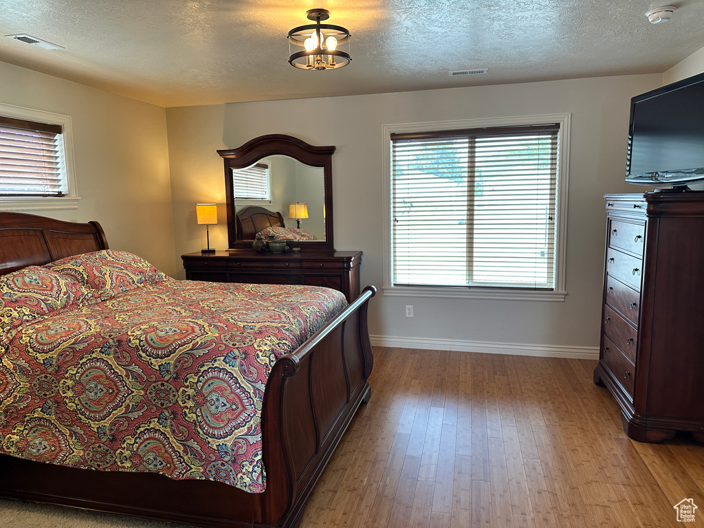 Bedroom featuring light wood-style floors, baseboards, and a textured ceiling