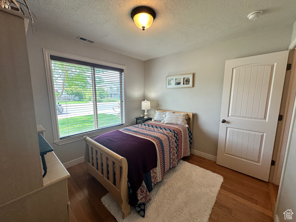 Bedroom with a textured ceiling, wood finished floors, and baseboards