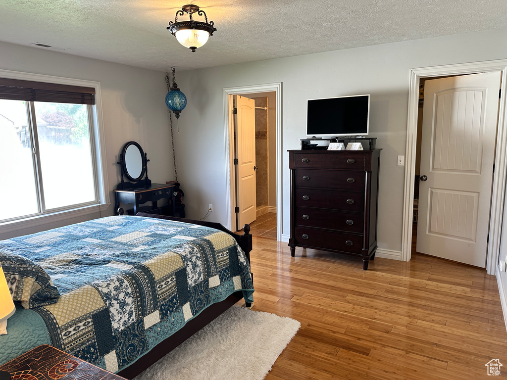 Bedroom with light wood-type flooring, a textured ceiling, and baseboards