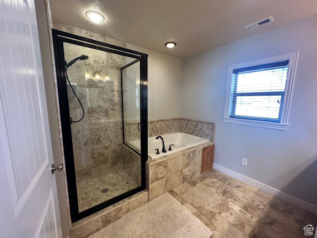Bathroom with a bath, a shower stall, and baseboards