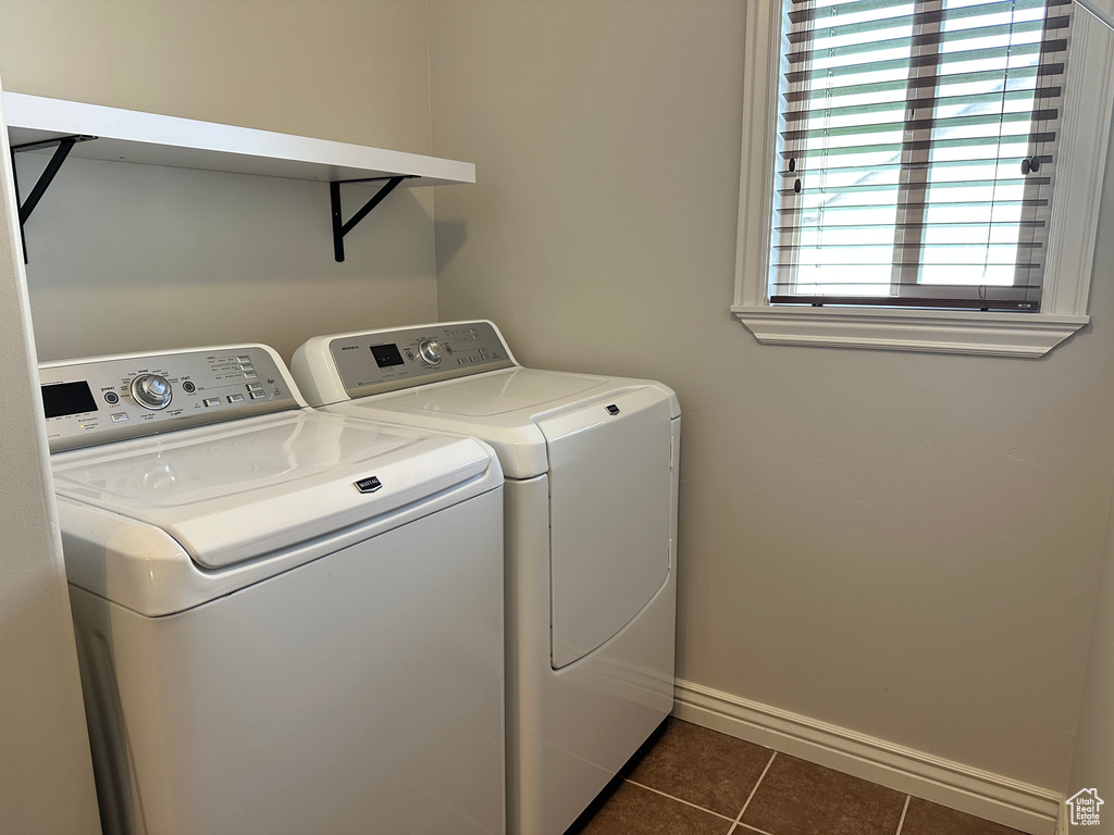 Washroom with washing machine and dryer, dark tile patterned floors, and baseboards