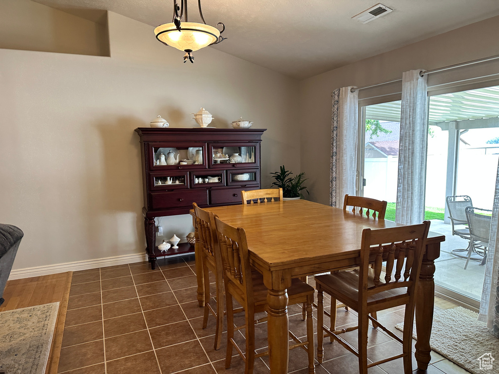 Dining space featuring vaulted ceiling, dark tile patterned flooring, and baseboards