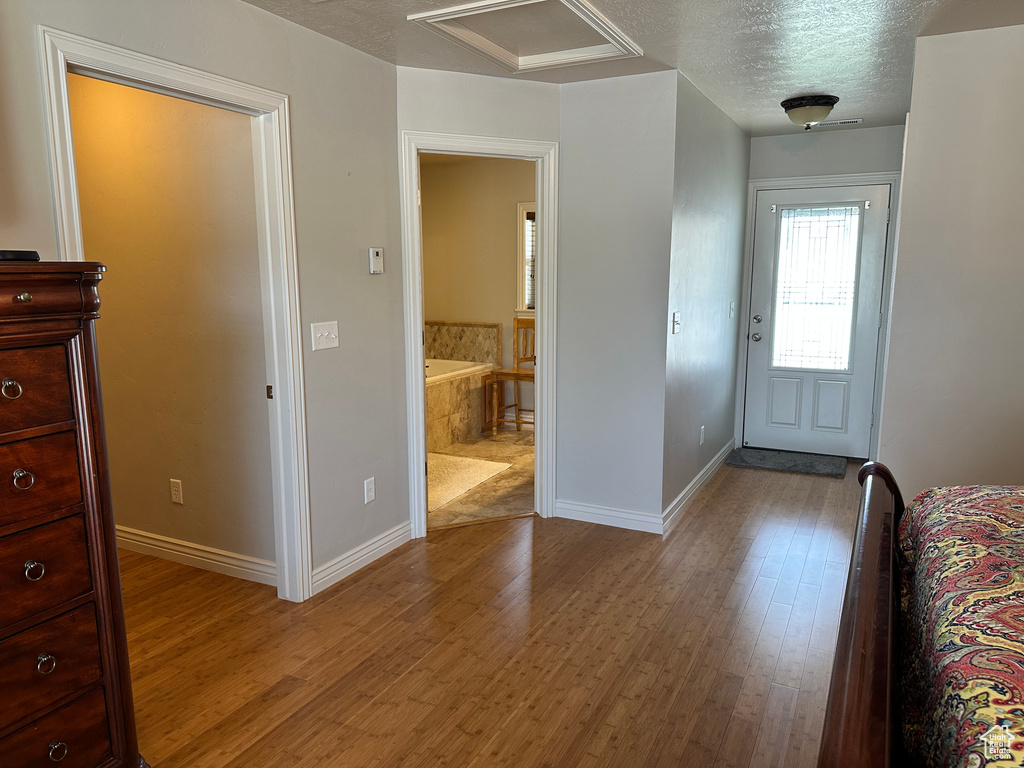 Foyer entrance with wood finished floors, a textured ceiling, and baseboards
