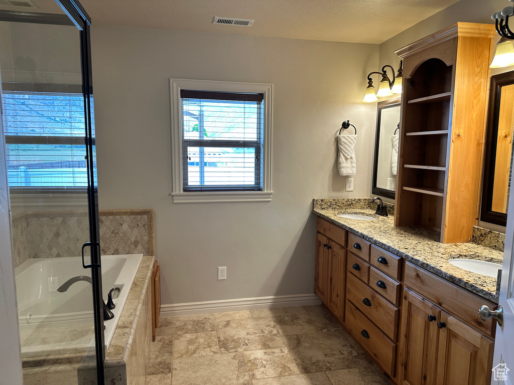 Bathroom with baseboards, double vanity, tiled tub, and a shower