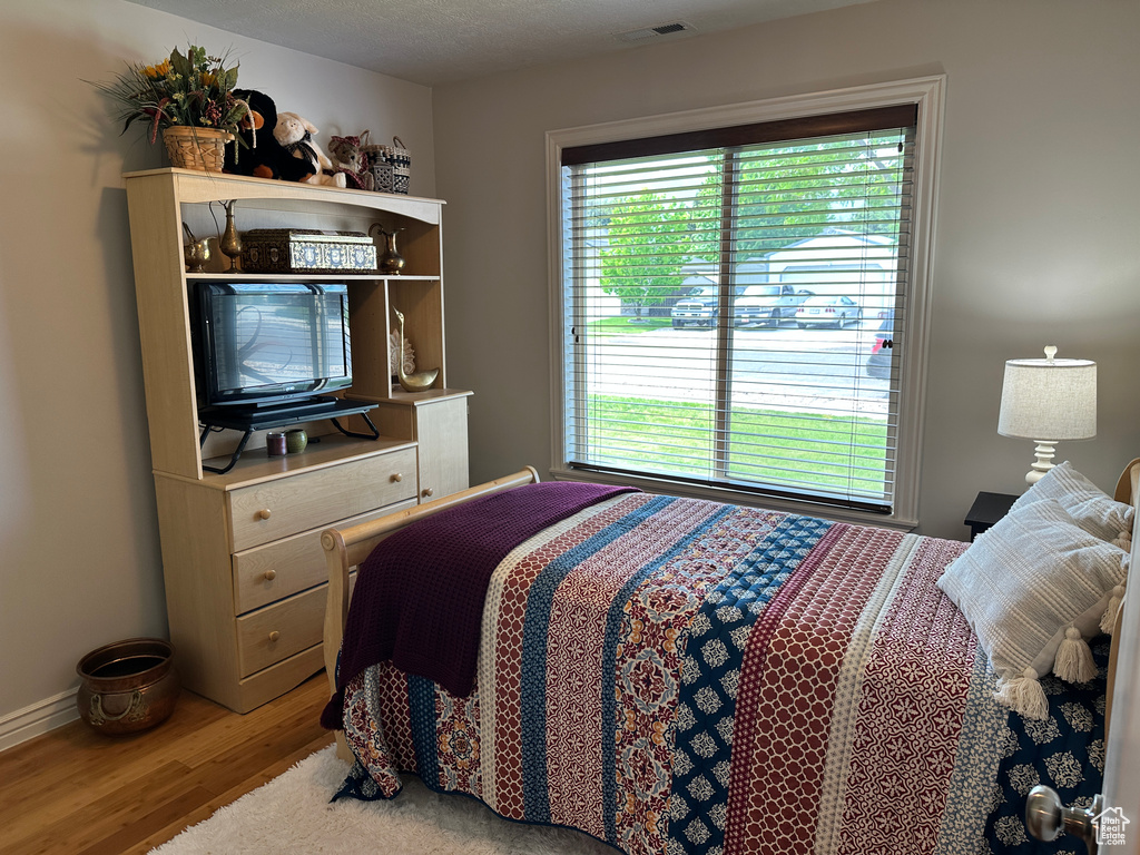 Bedroom with multiple windows, wood finished floors, and baseboards