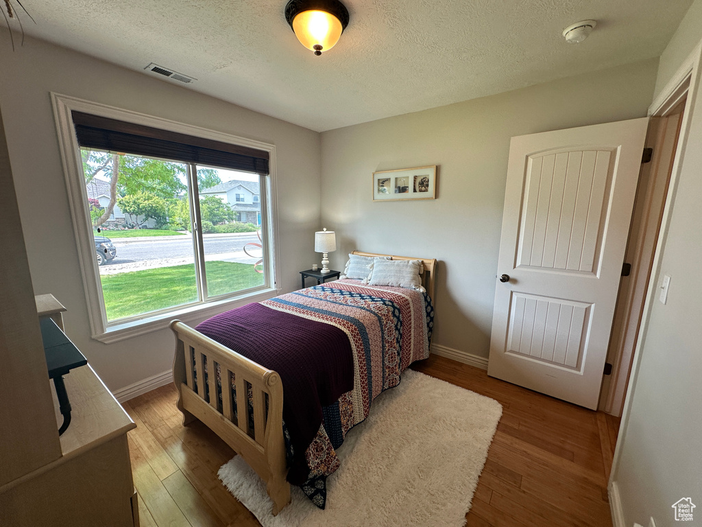 Bedroom with baseboards, wood-type flooring, and a textured ceiling