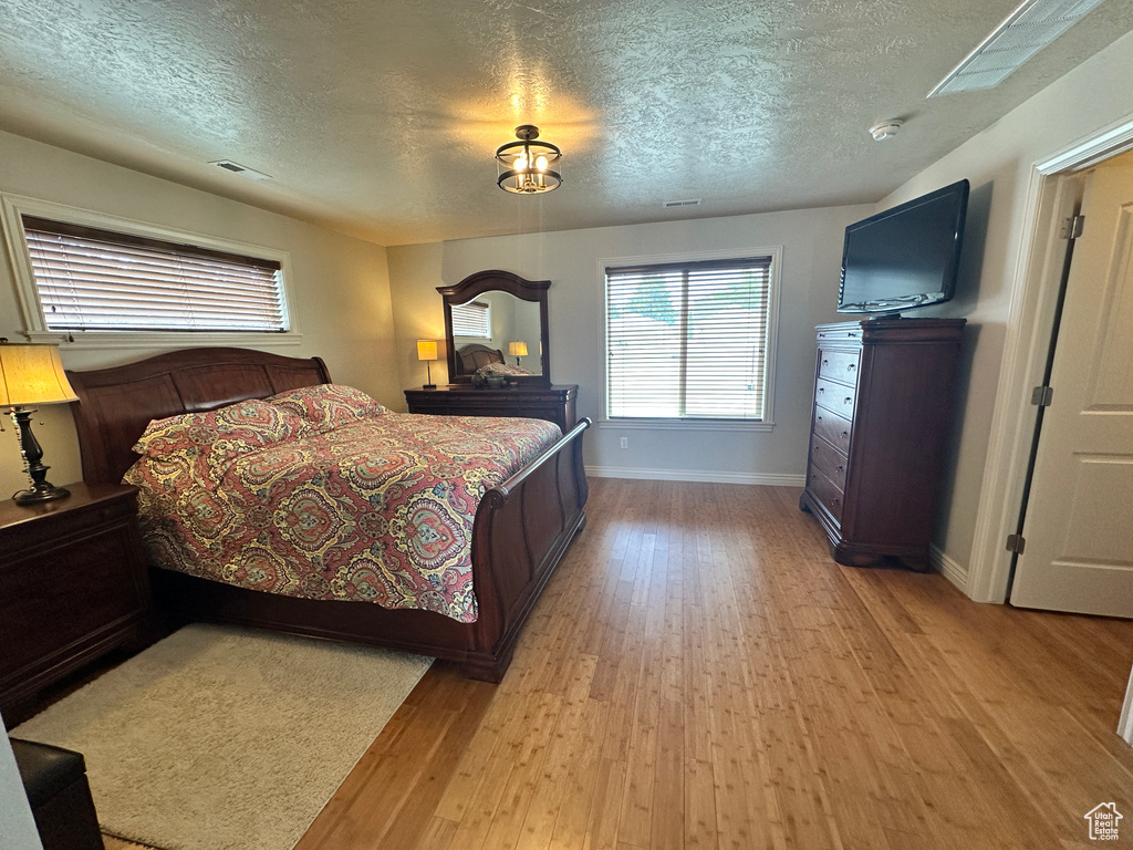 Bedroom featuring light wood-style flooring, a textured ceiling, and baseboards