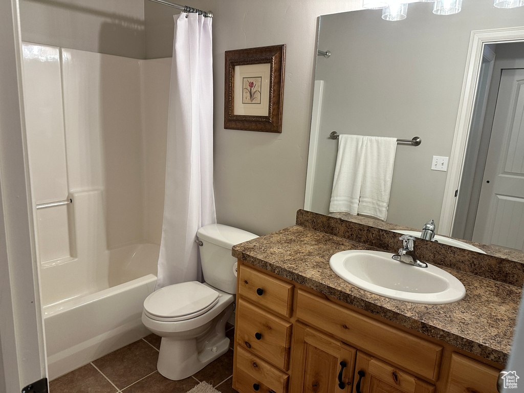 Bathroom with vanity, toilet, tile patterned floors, and shower / bathtub combination with curtain