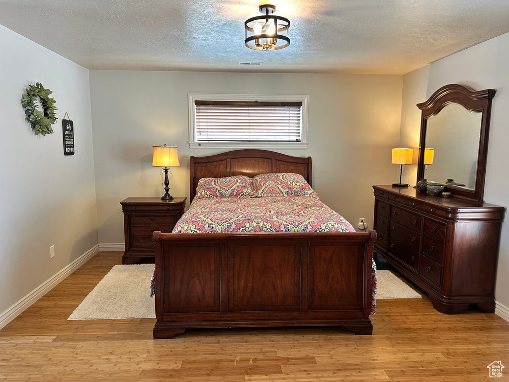 Bedroom with light wood-type flooring, baseboards, and a textured ceiling