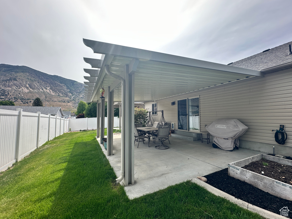 View of patio featuring area for grilling, a mountain view, and a vegetable garden