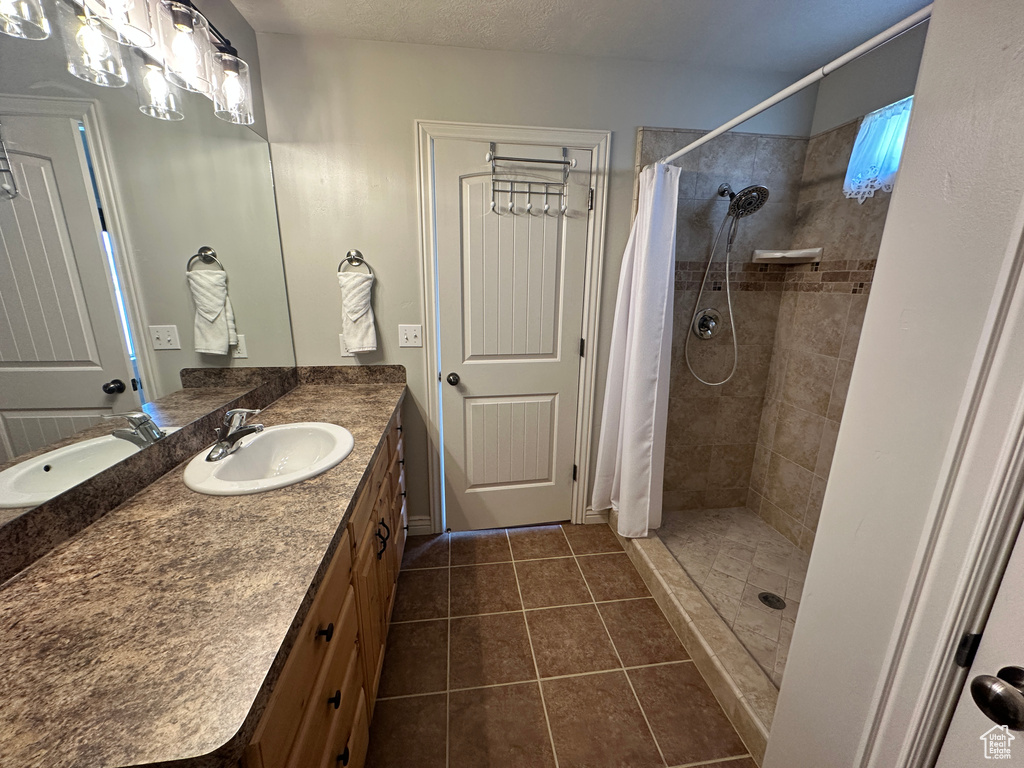 Bathroom featuring vanity, tile patterned flooring, and a tile shower