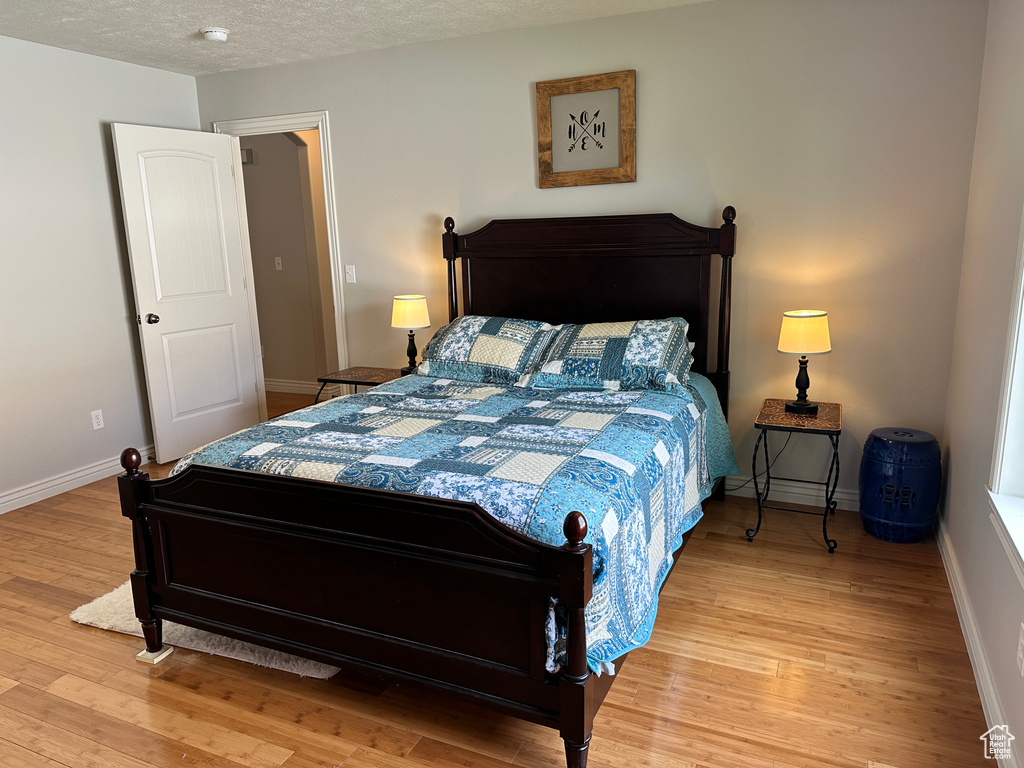 Bedroom with wood finished floors, baseboards, and a textured ceiling