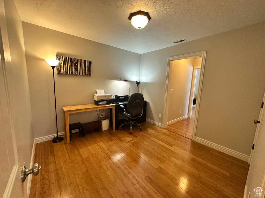 Office area featuring hardwood / wood-style flooring, baseboards, and a textured ceiling