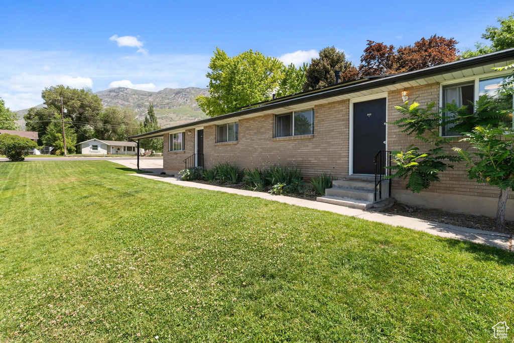 View of front of home featuring entry steps, a front yard, a mountain view, and brick siding