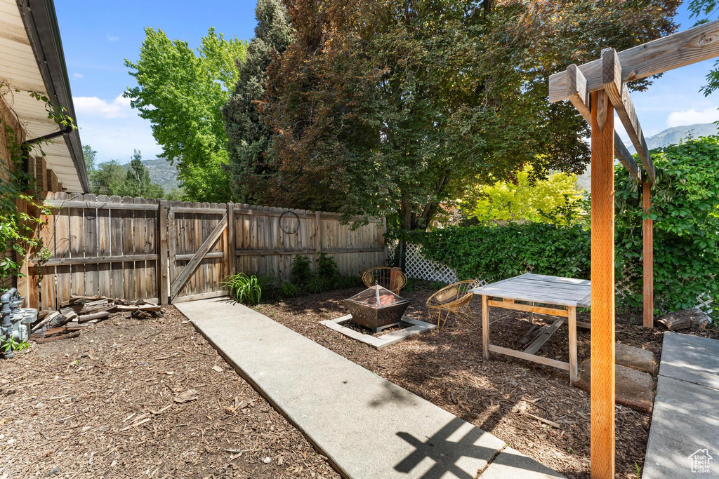 View of yard featuring a gate, an outdoor fire pit, and a mountain view