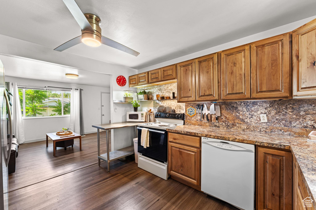 Kitchen with white appliances, decorative backsplash, a ceiling fan, and brown cabinetry