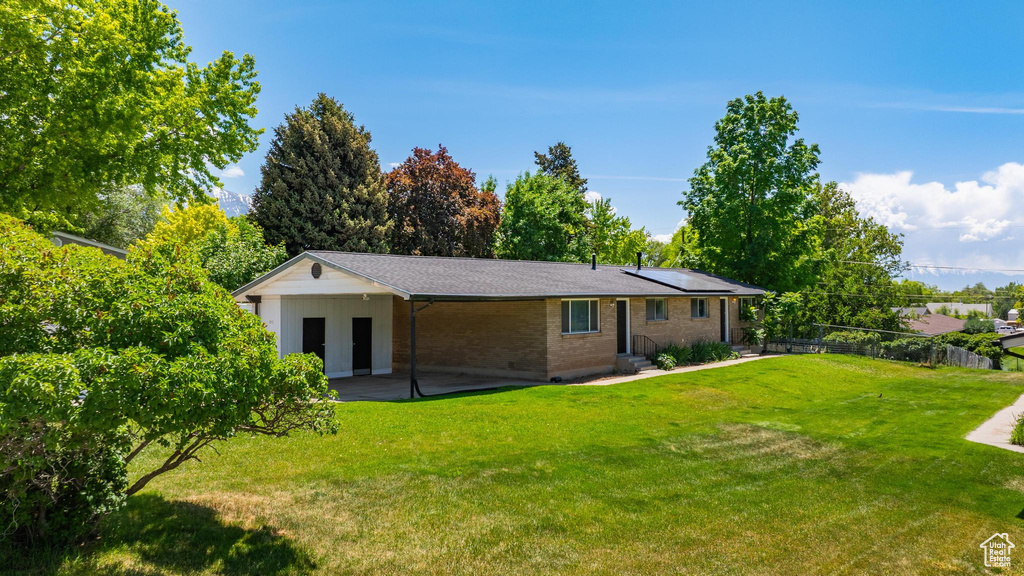 Rear view of property with brick siding, roof mounted solar panels, and a patio