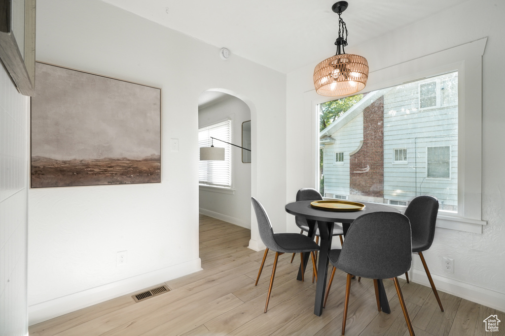 Dining area with arched walkways, baseboards, wood finished floors, and plenty of natural light