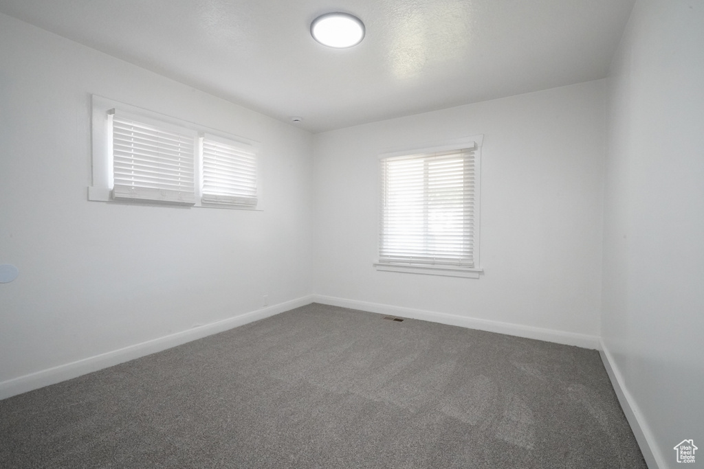 Empty room with dark carpet and baseboards